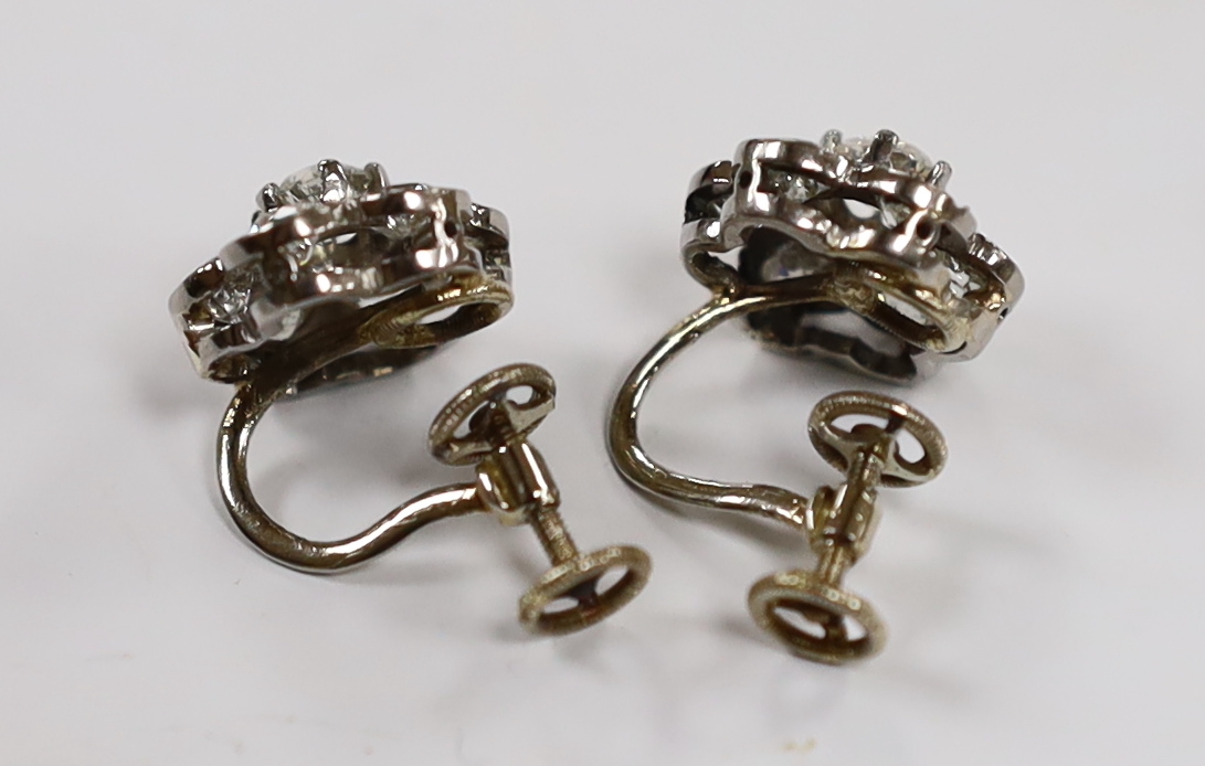 A pair of white metal and seven stone diamond set flower head cluster ear clips, 12mm, gross 4.9 grams.